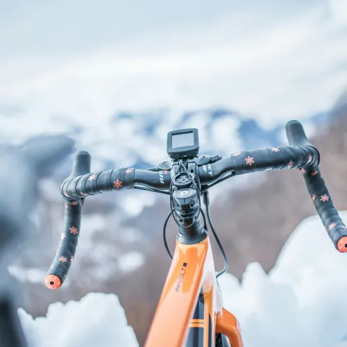 Oranssi py&ouml;r&auml; lumisessa maisemassa, ohjaustanko etualalla.