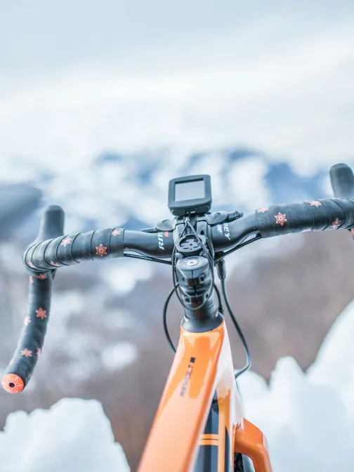 Oranssi py&ouml;r&auml; lumisessa maisemassa, ohjaustanko etualalla.