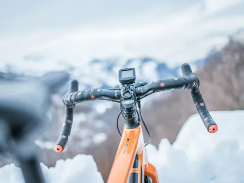 Oranssi py&ouml;r&auml; lumisessa maisemassa, ohjaustanko etualalla.